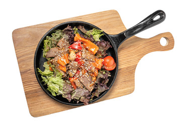 meat and vegetables in a frying pan on a white background
