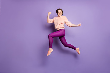 Fototapeta na wymiar Full body profile photo of pretty funky lady jumping up high rushing sale discounts shopping mall excited mood wear casual stylish sweater trousers isolated purple color background
