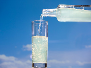 Naklejka na ściany i meble Lemon carbonated drink pours from a bottle into a glass