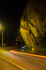 motorcycle tale lights on a night road under a rock