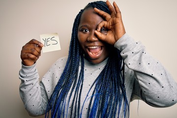 Young african american plus size woman with braids holding reminder paper with yes message with...