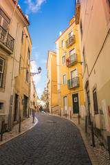winding Lisbon street with yellow houses against a blue sky