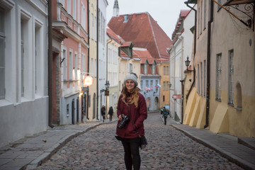 Fototapeta premium cute female photographer walking down the old streets of telling estonia