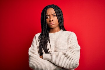 Young african american woman wearing casual winter sweater over red isolated background skeptic and...