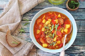 Spicy split pea soup with potatoes, tomatoes, sausages and slices of bread