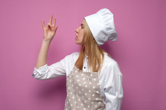 cheerful girl cook in kitchen clothes shows a belissimo gesture on a colored background, a woman housewife shows a sign of good taste
