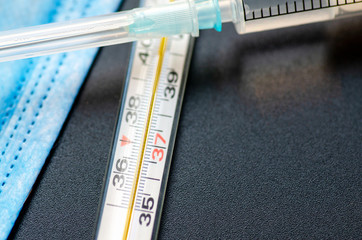 Syringe with medicine for the virus, medical protective mask and thermometer, concept of...