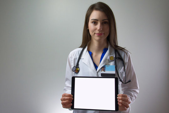 Female Healthcare Worker Holding Tablet Towards Camera. Blank For Text Or Copy, Technology In Healthcare Including White Coat And Stethoscope