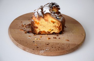 Kraffin Easter cake in powdered sugar with raisins, dried apricots and nuts on wooden cutting board
