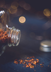 bottle filled with chili layed on a dark backround. bokeh light in the background. close-up