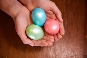 Fototapeta na wymiar Colored Easter eggs in the palms of your hands. Three eggs painted pink green and blue.