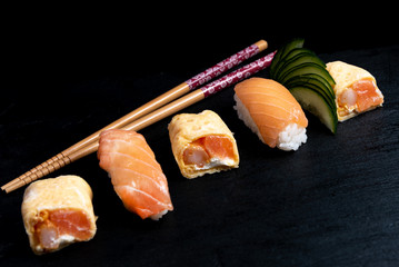 Japanese cuisines nigiri sushi set on black plate served with wasabi, soy sauce. Sushi Roll with salmon, sushi maki roll and tamago sushi on black plate