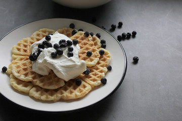 Pancakes with whipped cream, berry sauce and berries over dark background. Close up.