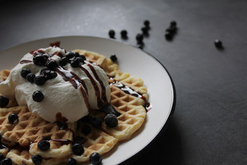 Pancakes with whipped cream, berry sauce and berries over dark background. Close up.