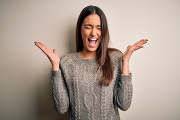 Young beautiful brunette woman wearing casual sweater over isolated white background celebrating...