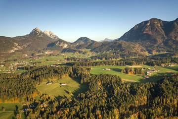 Aerial view of green meadows with villages and forest in austrian Alps mountains.