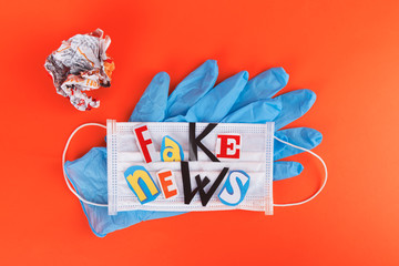 L'insciption Fake news, collage of colored paper's letters, with medical face mask and blue protective gloves. The concept of lies in social networks during the world coronavirus pandemic