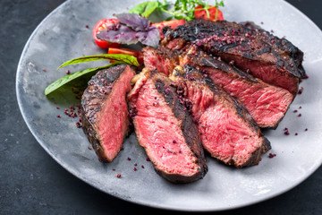 Barbecue dry aged wagyu entrecote beef steak with lettuce and tomatoes as closeup on a modern...