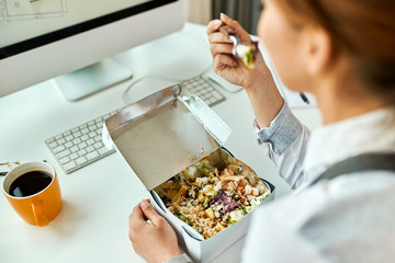 Close-up of businesswoman having a healthy meal while working in the office.