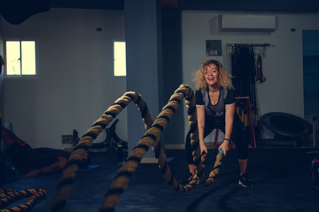 Blonde woman using the battle rope in a gym