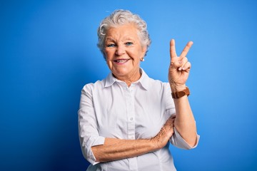 Senior beautiful woman wearing elegant shirt standing over isolated blue background smiling with...