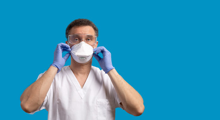 A male doctor in white uniformput puts on the protective surgical mask