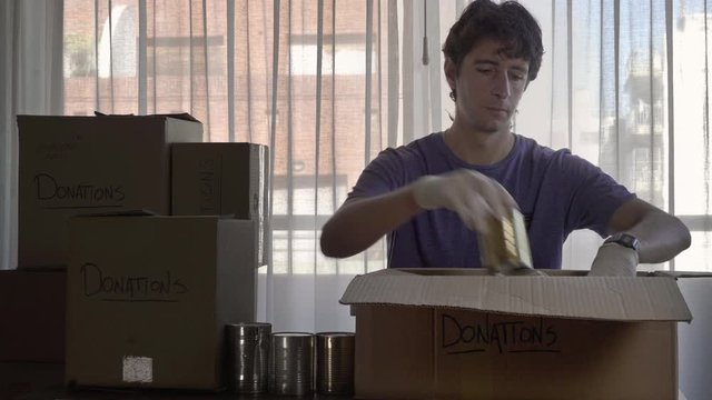 Man preparing box of donations with canned food