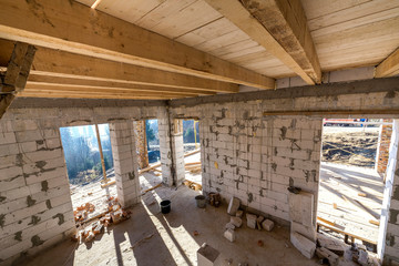 House room interior under construction and renovation. Energy saving walls of hollow foam insulation blocks, wooden ceiling beams and roof frame.