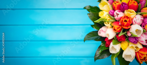 Colorful bouquet of tulips on blue wooden background. Spring flowers. Greeting card with copy space for Valentine's Day, Woman's Day and Mother's Day. Top view