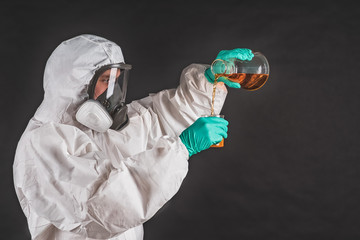 Biologist in protective clothing analyzing liquid reagent in laboratory glassware.