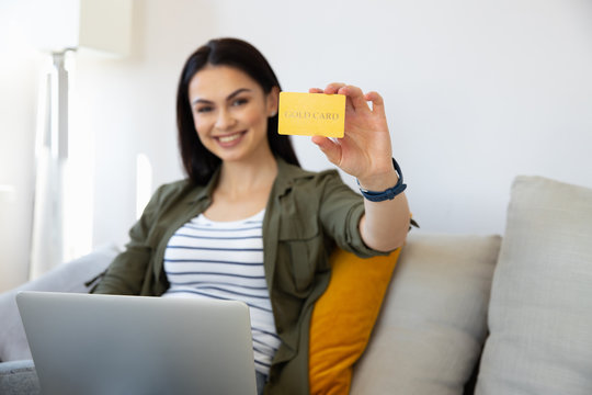 Joyful young woman with laptop holding gold card