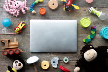 A laptop surrounded with children's toys. 
