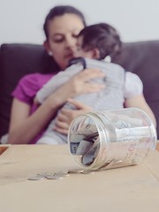 Problemas económicos por pandemia, madre y bebé con ahorro de dinero en un recipiente de vidrio 