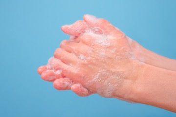 Hands washing with bubble soap on blue background. Washing hands with soap on medical blue background. Hygiene. Cleaning Hands. Protection from virus. Basic rules during pandemic