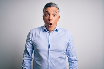 Middle age handsome grey-haired business man wearing elegant shirt over white background afraid and shocked with surprise expression, fear and excited face.