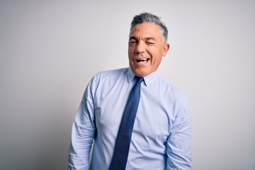 Middle age handsome grey-haired business man wearing elegant shirt and tie winking looking at the camera with sexy expression, cheerful and happy face.