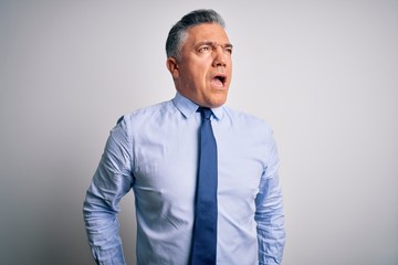 Middle age handsome grey-haired business man wearing elegant shirt and tie angry and mad screaming frustrated and furious, shouting with anger. Rage and aggressive concept.