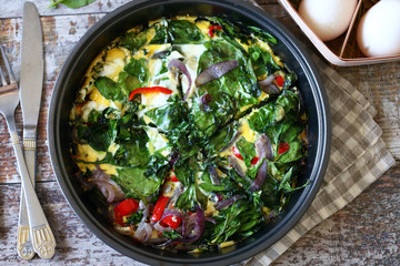 Selective focus. Healthy homemade omelet with spinach and vegetables. Spinach omelet in a pan. Cooking healthy food at home.