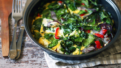 Selective focus. Healthy homemade omelet with spinach and vegetables. Spinach omelet in a pan. Cooking healthy food at home.