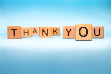 Thank you background. Word thank you made with wooden cubes on blue background. Message of...
