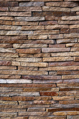 Stone cladding wall made of striped stacked slabs of natural brown rocks. Panels for exterior. Texture for designers natural pebbles