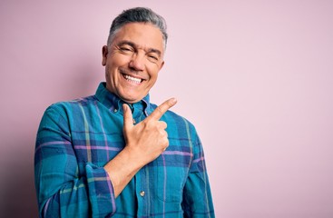 Middle age handsome grey-haired man wearing casual shirt over isolated pink background cheerful with a smile of face pointing with hand and finger up to the side with happy and natural expression