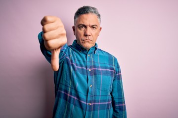 Fototapeta premium Middle age handsome grey-haired man wearing casual shirt over isolated pink background looking unhappy and angry showing rejection and negative with thumbs down gesture. Bad expression.