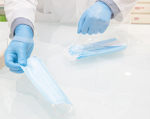 Close-up of doctor with blue medical gloves are selling surgical masks