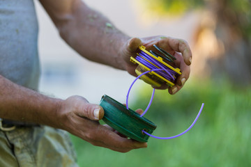 Lawn mower pulls the line out of the trimmer coil - maintenance of garden tools, close up trimmer...