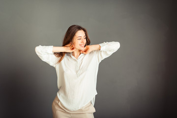 Young girl in a white shirt, hands up, on a gray background. Honest and emotional on the banner,...