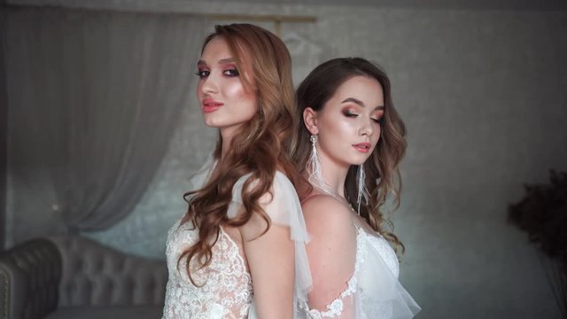 Two young models posing in front of the photographer in a wedding dress.