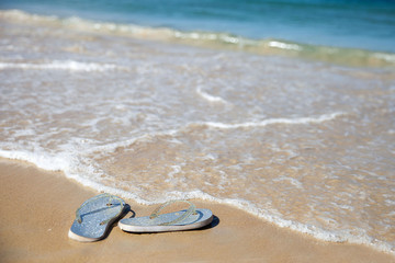 Silver flip flops on a sandy beach
