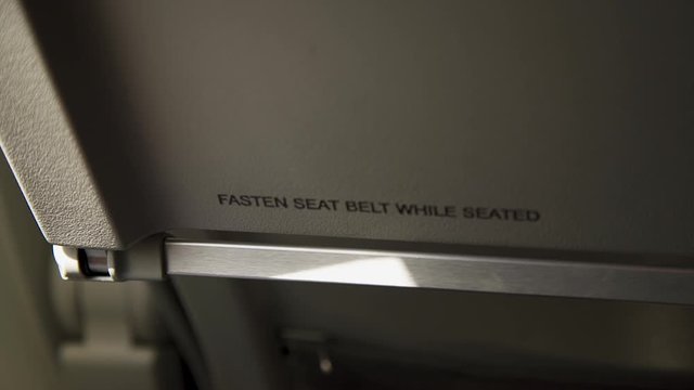 airline passengers view of sunlight moving across fasten seatbelt sign