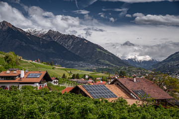 Panorama of solar batteries on roof top, green slopes of the mountains of Italy, Trentino, Dolomites, huge clouds over a valley, green meadows, a clear energy, energy of the sun, Solar panels